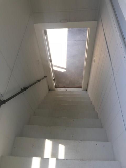Interior staircase leading to a glass-panel door, with sunlight falling across the steps.