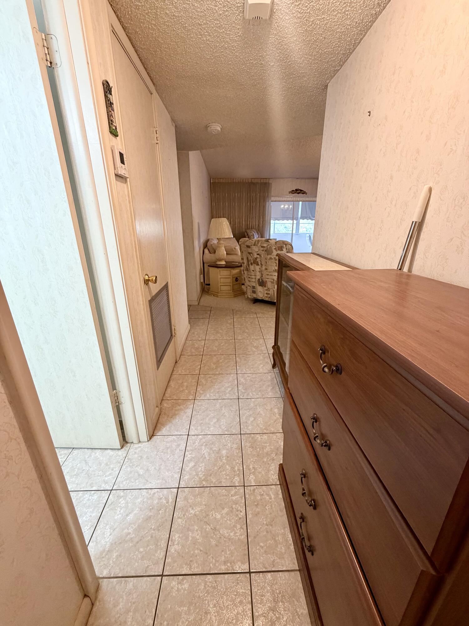 Tiled entry hallway with a large wooden dresser and furnished living room beyond.