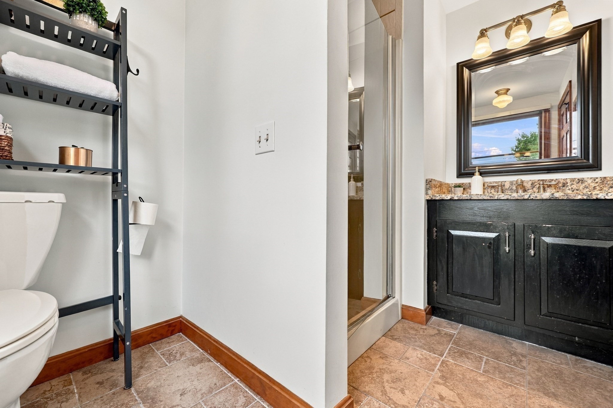 Bathroom with a glass shower and black vanity topped with granite.