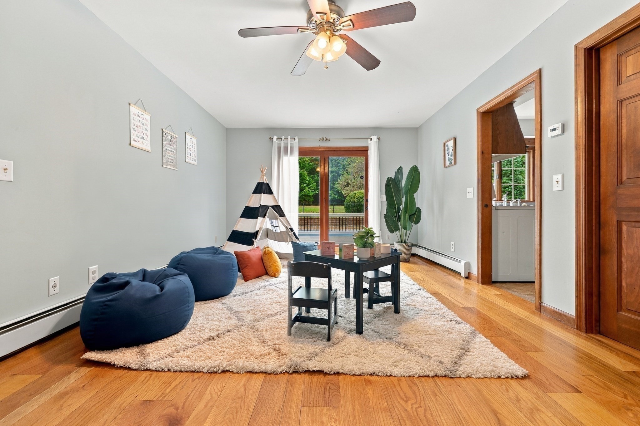 Playroom with navy beanbag chairs, a striped teepee, and glass doors to a deck.