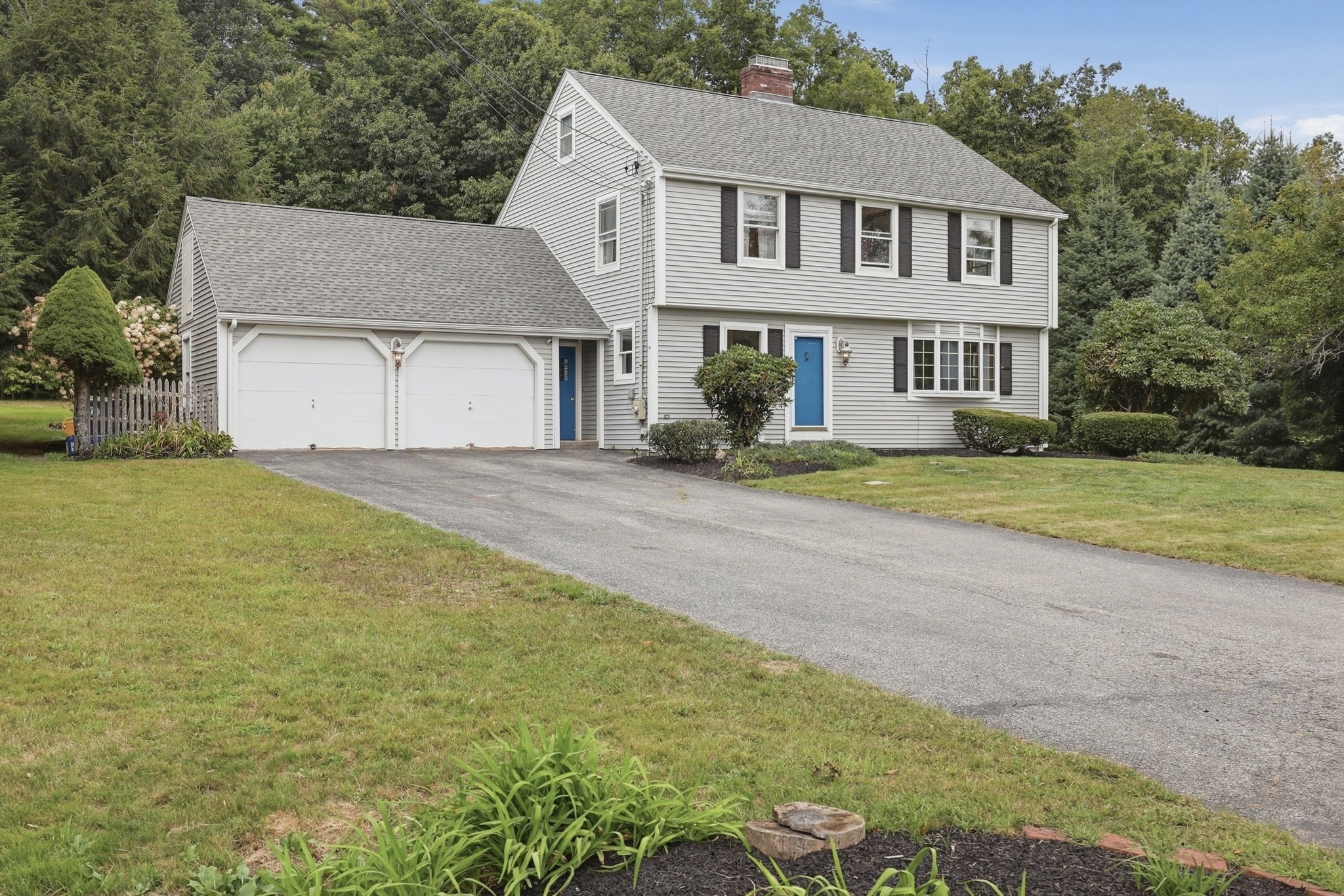 Two-story gray house with blue doors, black shutters, and an attached two-car garage.