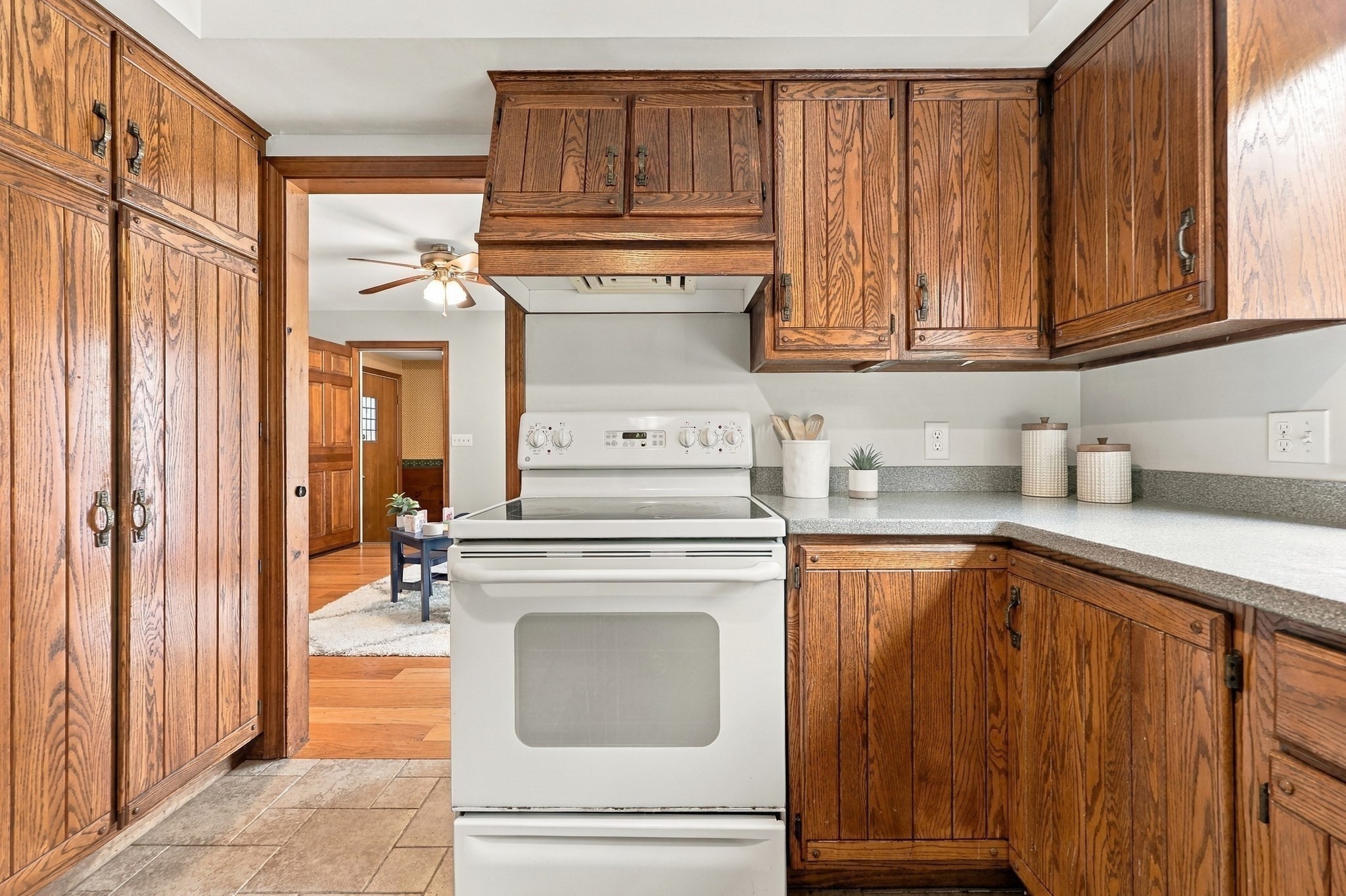 Kitchen with extensive wood cabinetry, gray countertops, and a white range.