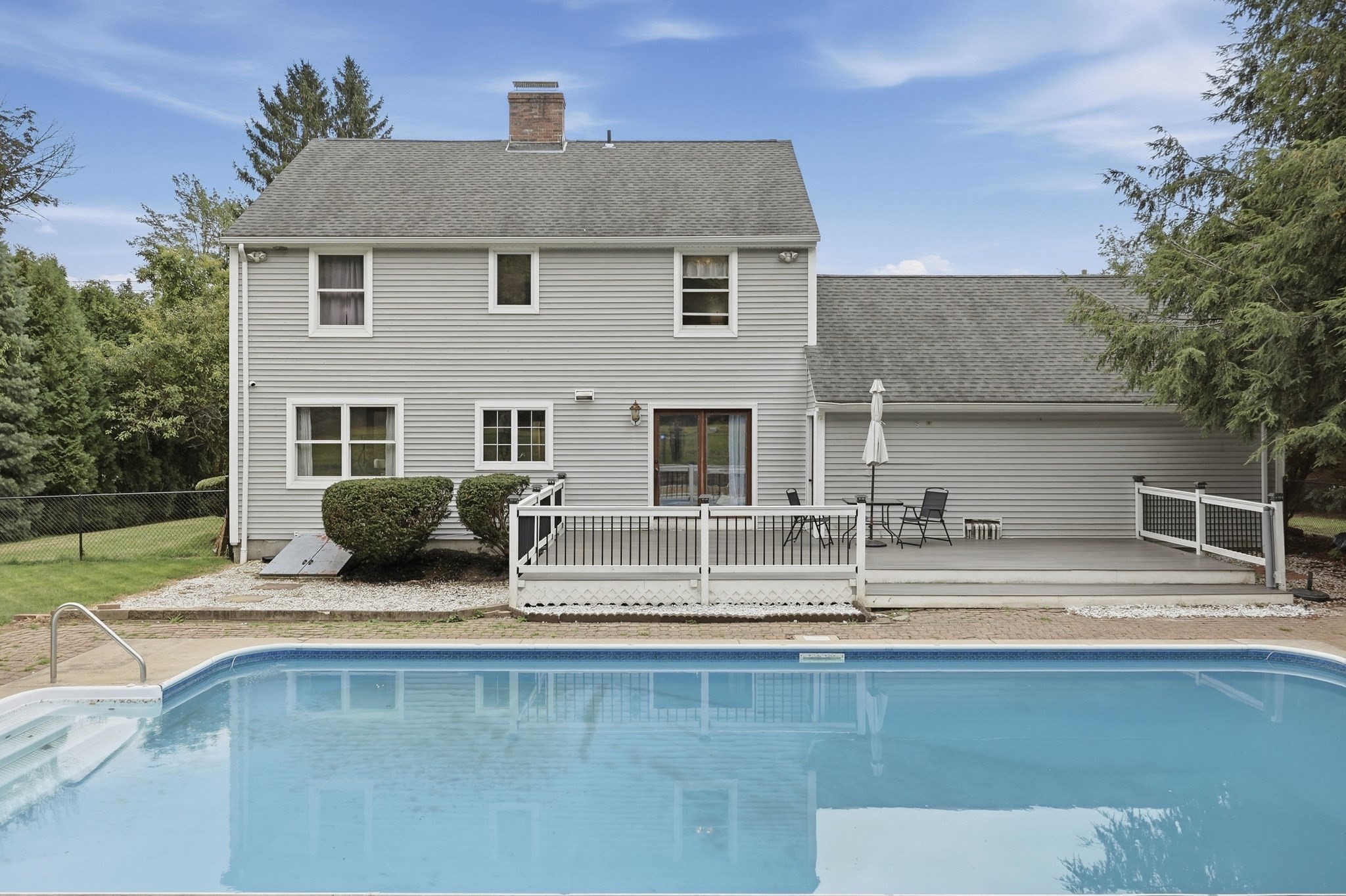 Two-story gray house with a furnished deck and swimming pool in the foreground.