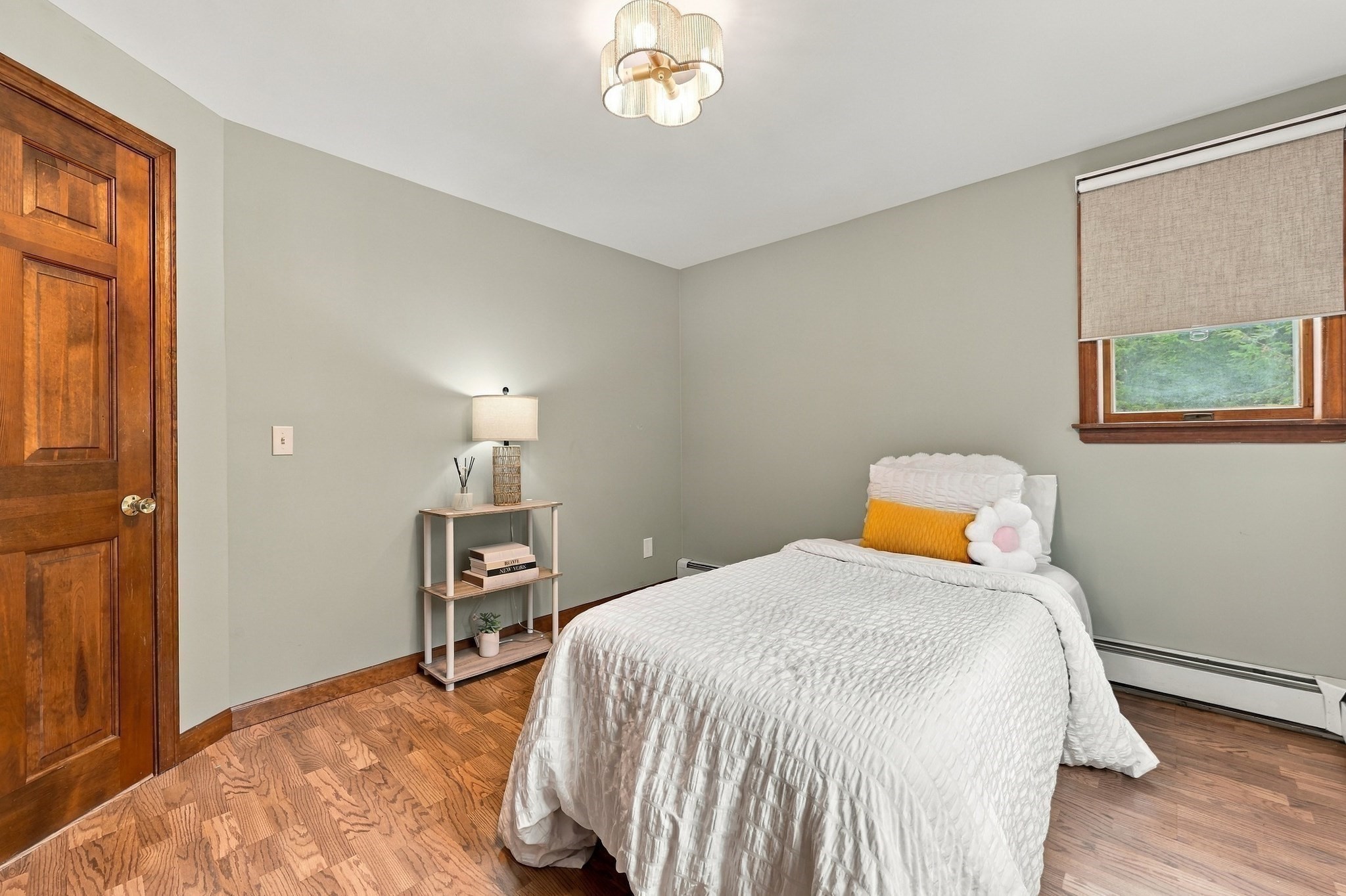 Bedroom with a white quilted bed, hardwood floors, and a wooden paneled door.