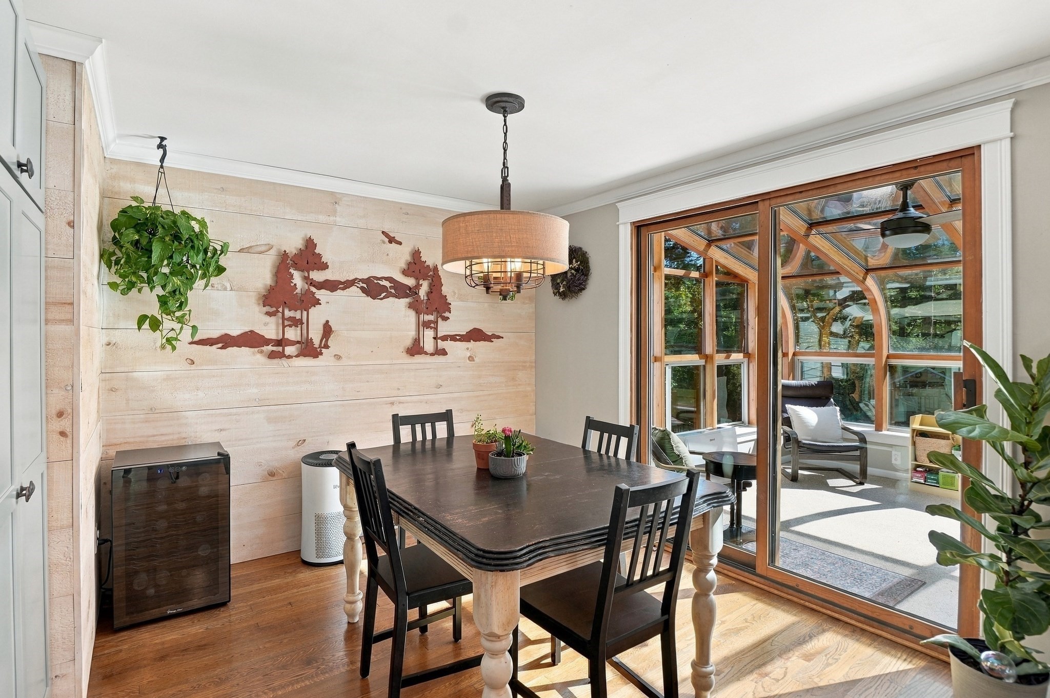 Dining room with a dark wood table beside glass doors opening to a sunroom.