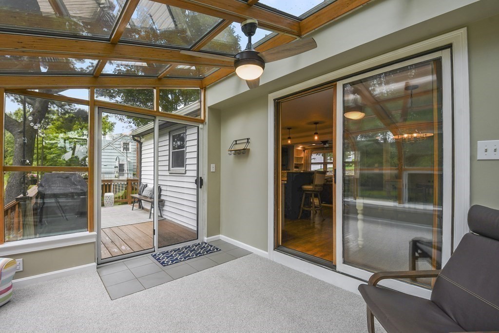 Sunroom with a glass-and-wood ceiling and sliding doors opening onto a wooden deck.