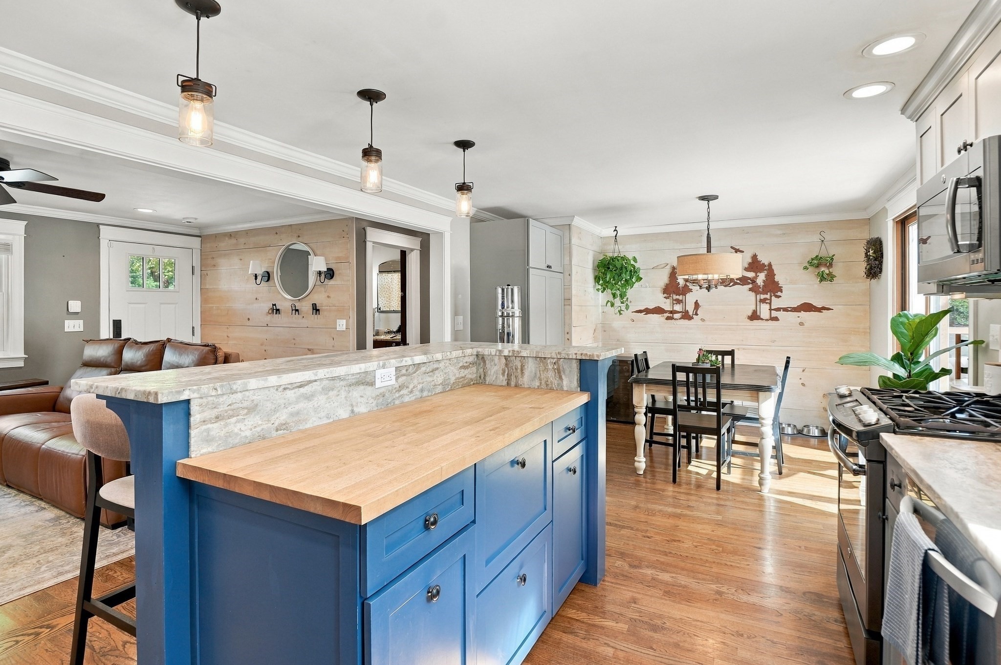 Open-plan kitchen with a blue island, pale stone counters, and dining area.
