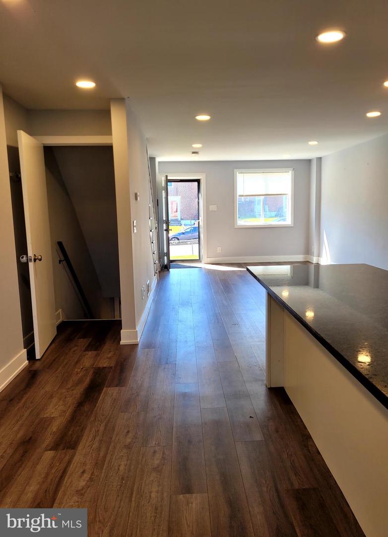Open-plan kitchen with a large island, dark wood floors, and recessed lighting.