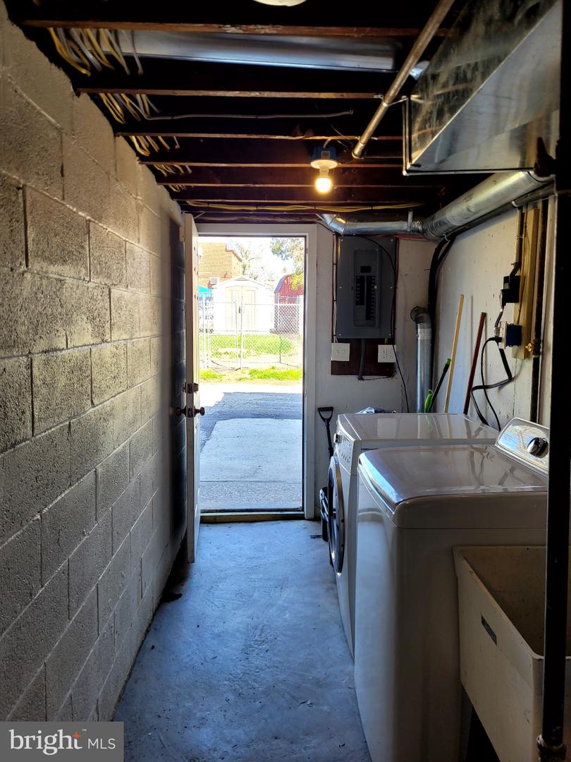 Basement laundry area with washer and dryer, exposed ceiling joists, and an open exterior door.