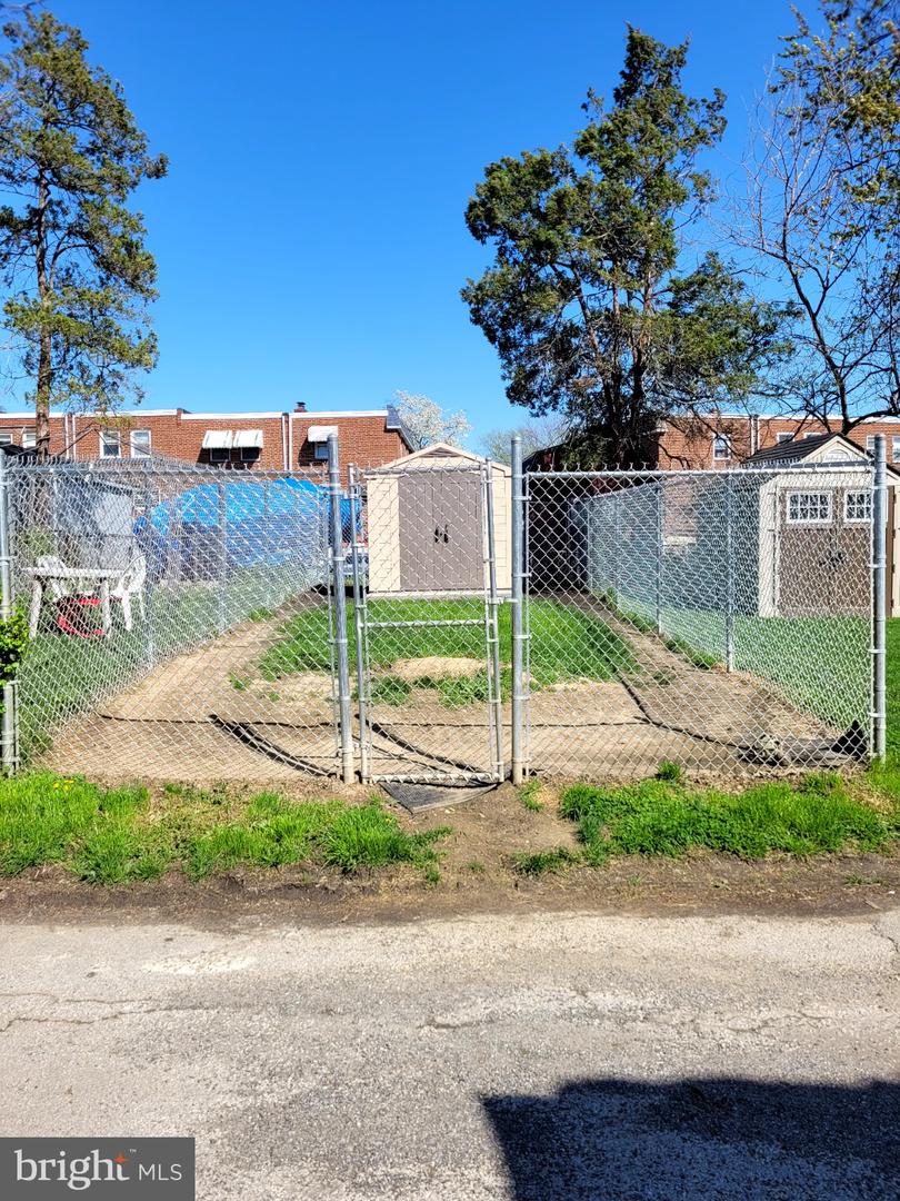 Fenced backyard with a concrete path, central gate, and two storage sheds.