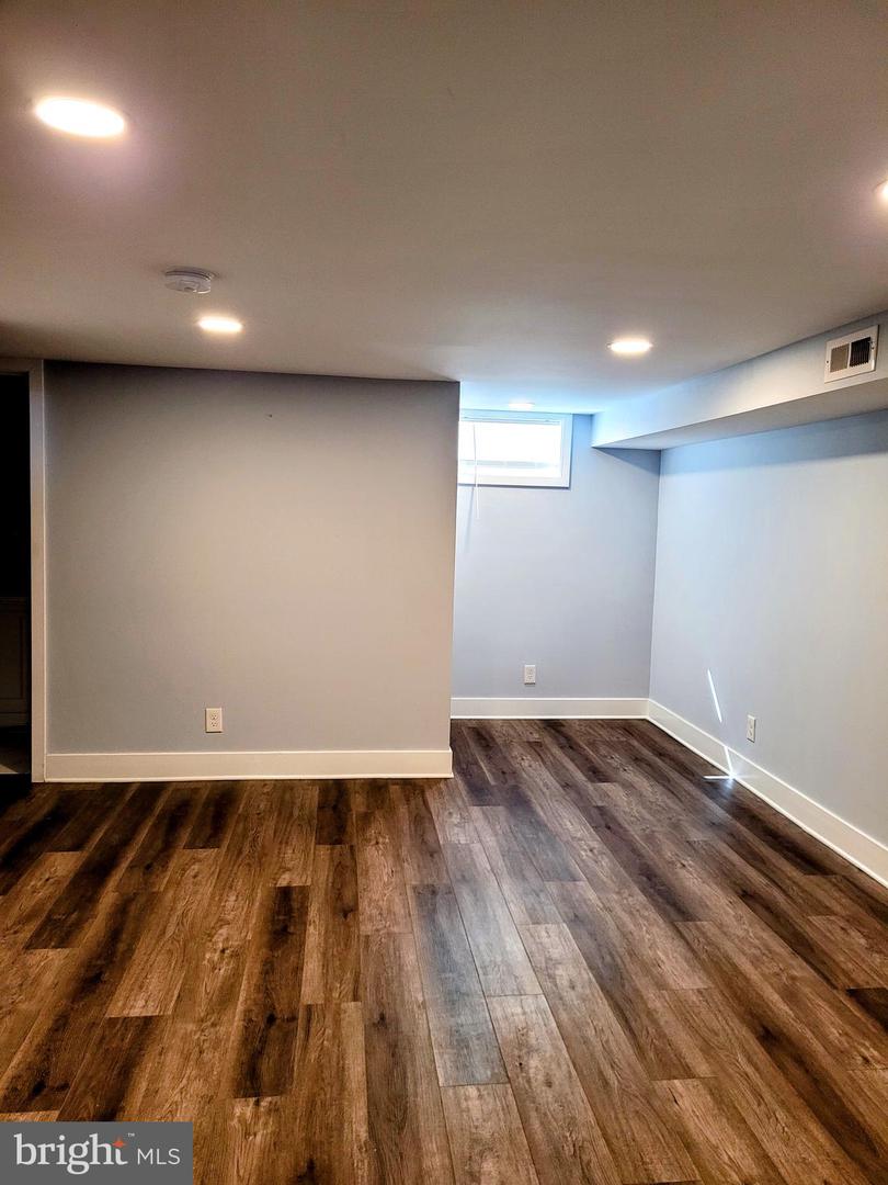 Empty finished basement with dark wood-look flooring and a small high-set window.