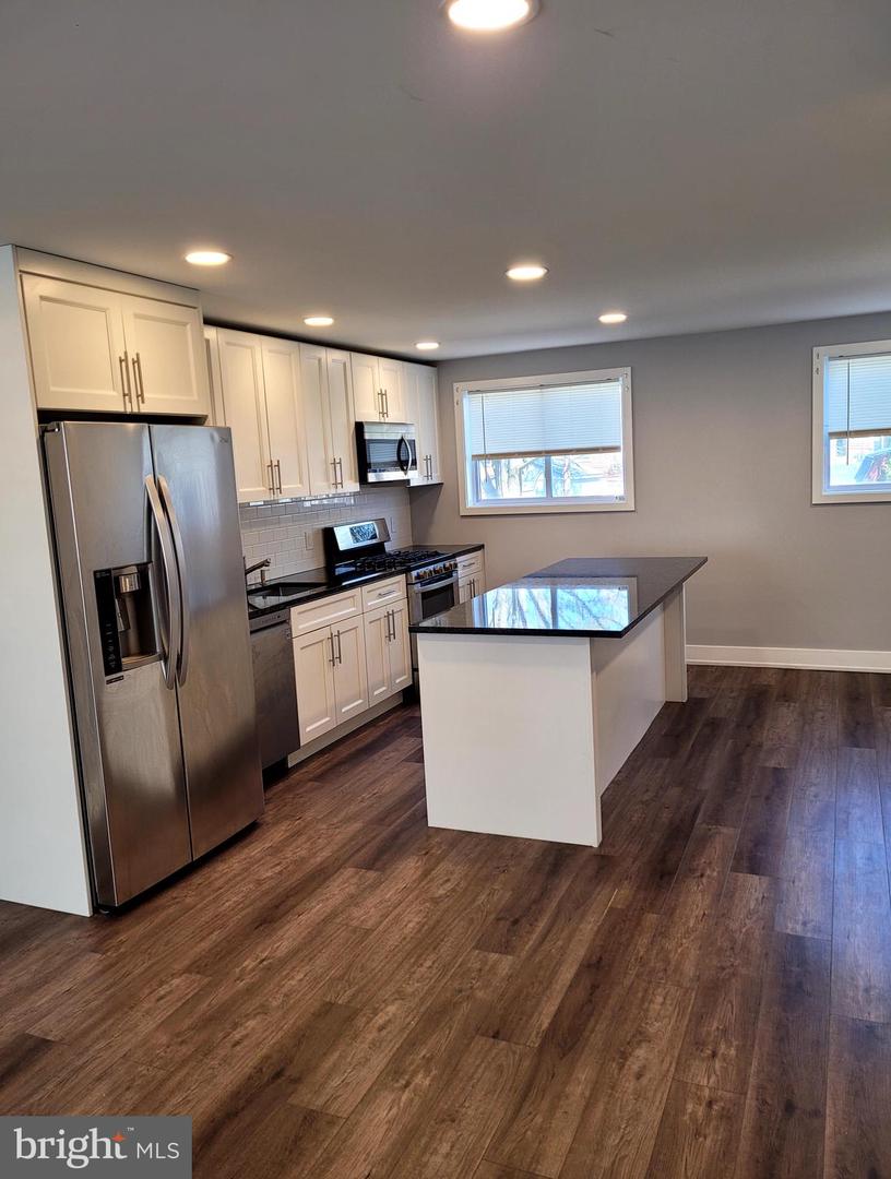Kitchen with white cabinetry, stainless steel appliances, and a dark-topped island.