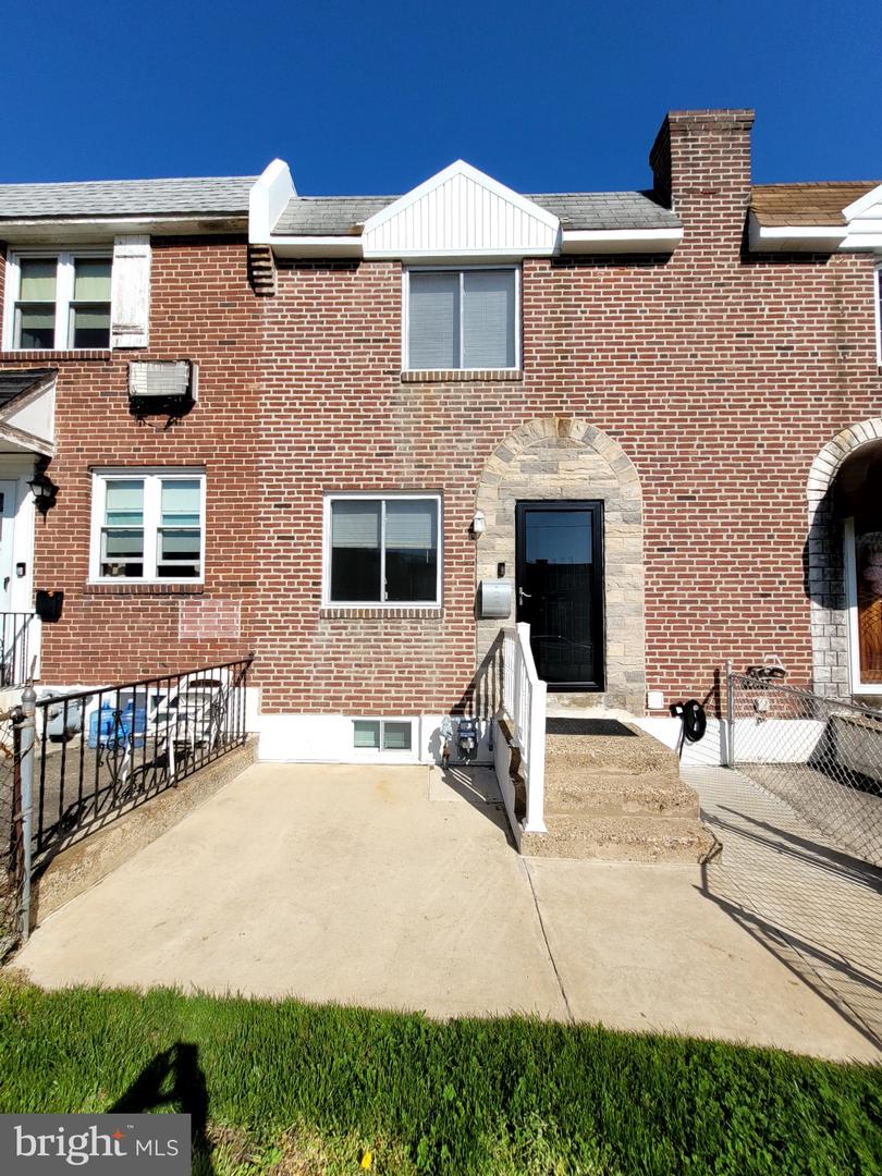 Red-brick attached home with a stone-arched entrance and concrete front walkway.
