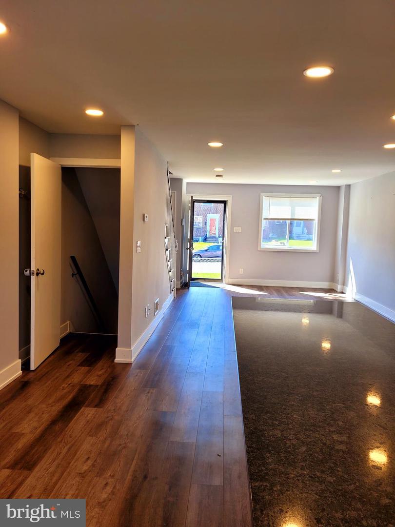 Unfurnished interior with wood-look and glossy dark flooring, recessed lights, and a window beside the exterior door.