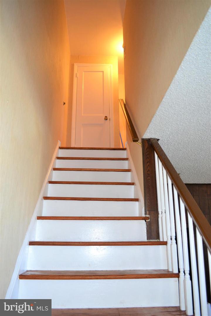 Staircase with white risers, dark wood treads and railing, leading to a closed door.