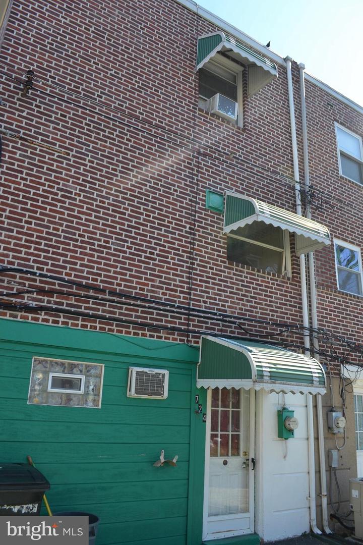 Brick building exterior with green siding, white entry doors, and green-and-white striped awnings.
