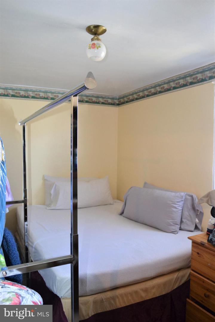 Bedroom with a white canopy bed, pale yellow walls, and a floral border near the ceiling.