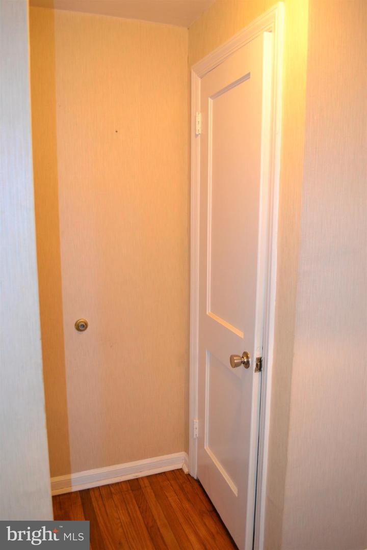 Narrow hallway with hardwood floors and a partly open white paneled door.