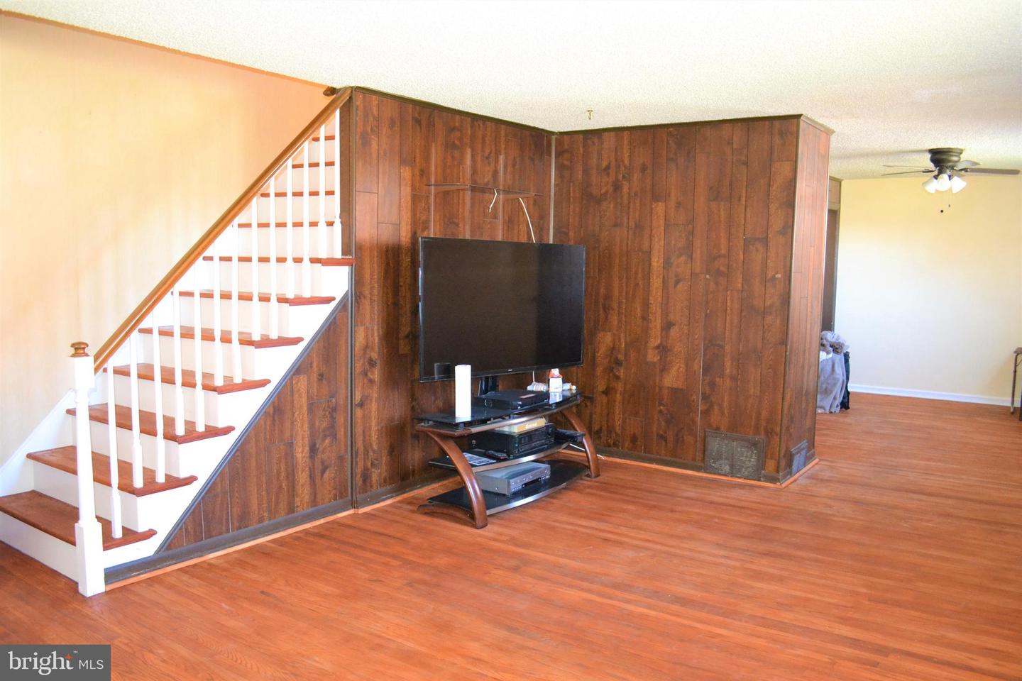 Living room with a wood-paneled partition, staircase, and television stand.