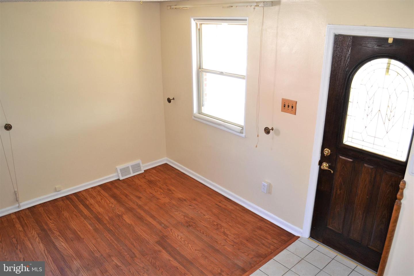 Vacant entryway with hardwood floors, a window, and a dark wood front door with decorative glass.