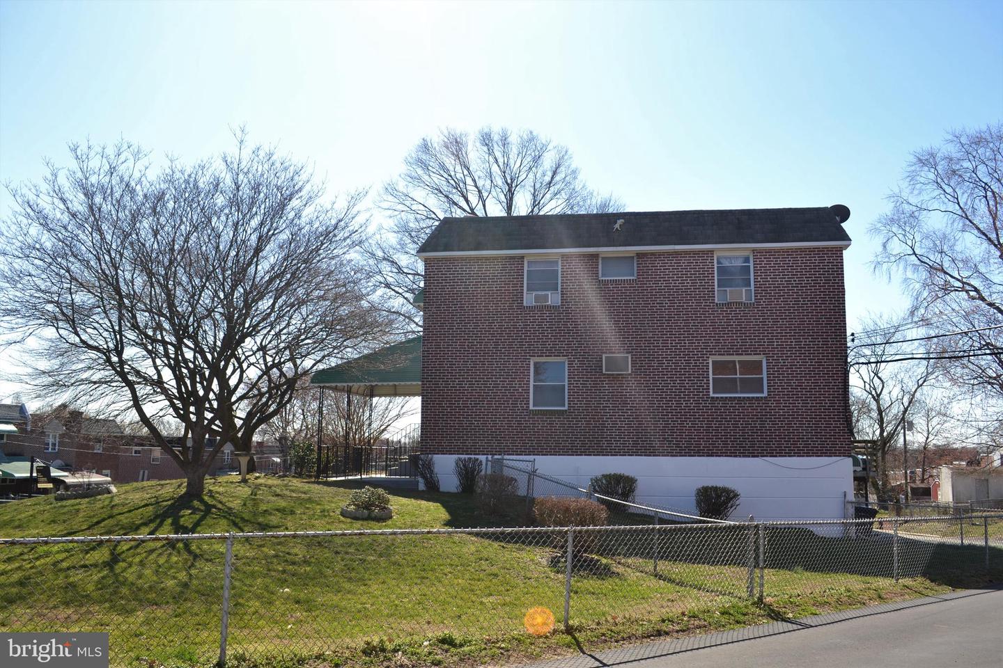 Two-story brick house with a fenced grassy yard and covered patio.