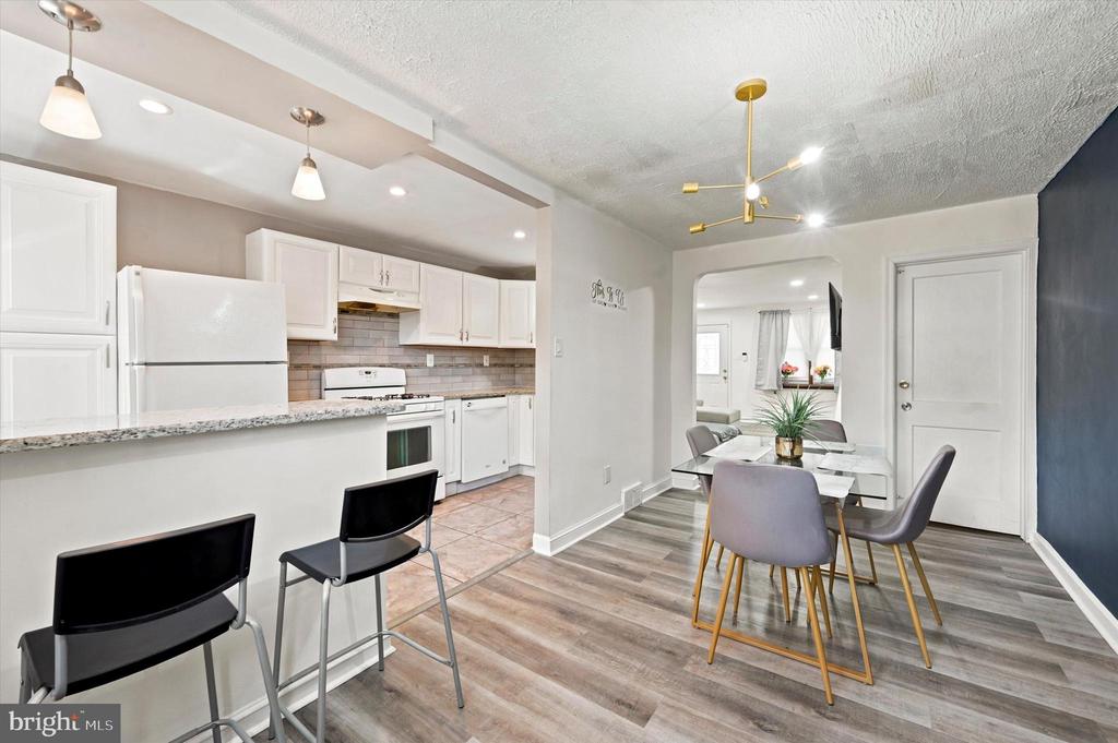 Kitchen and dining area with white cabinetry, a breakfast bar, and gray wood-look flooring.