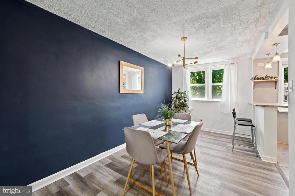 Dining room with a glass-top table, navy accent wall, and bright windows.