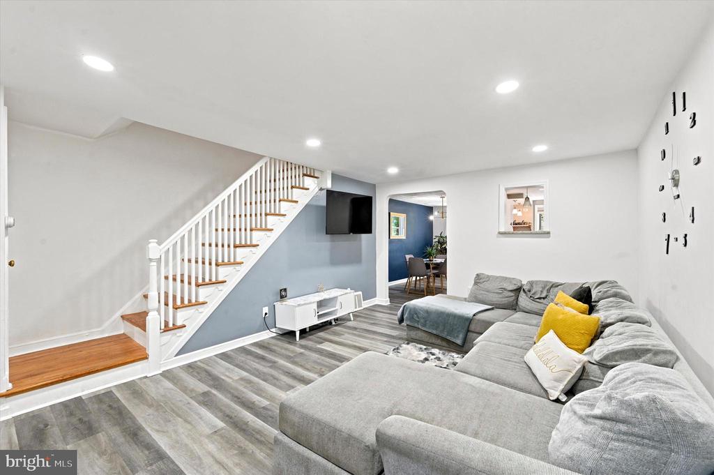 Living room with a large gray sectional, wood-and-white staircase, and blue accent wall.