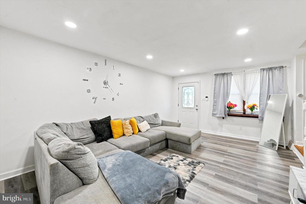 Living room with a gray sectional, yellow accent pillows, and gray wood-look flooring.