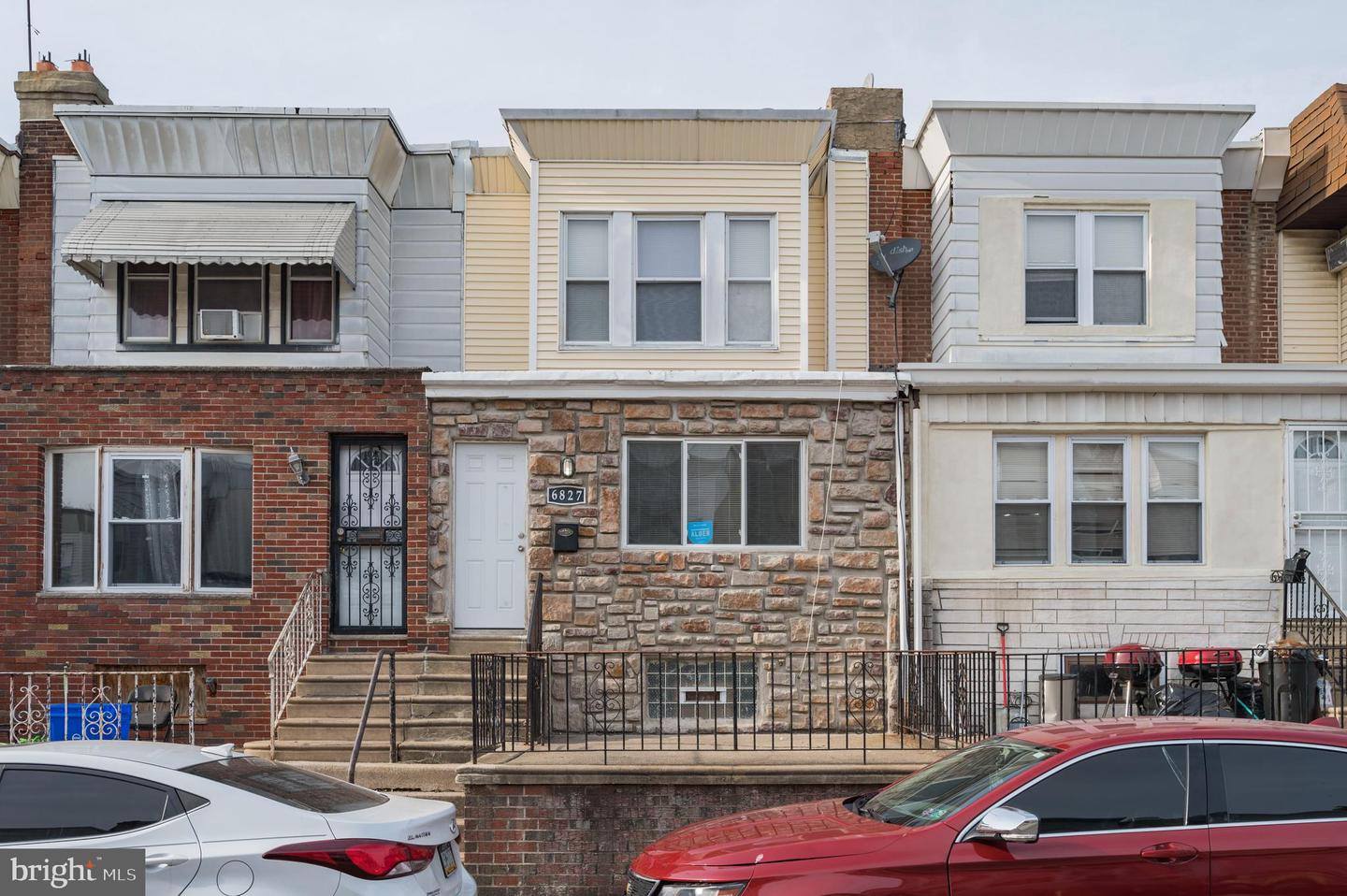 Rowhouse at 6827 Guyer Avenue with a stone facade and pale yellow upper siding.