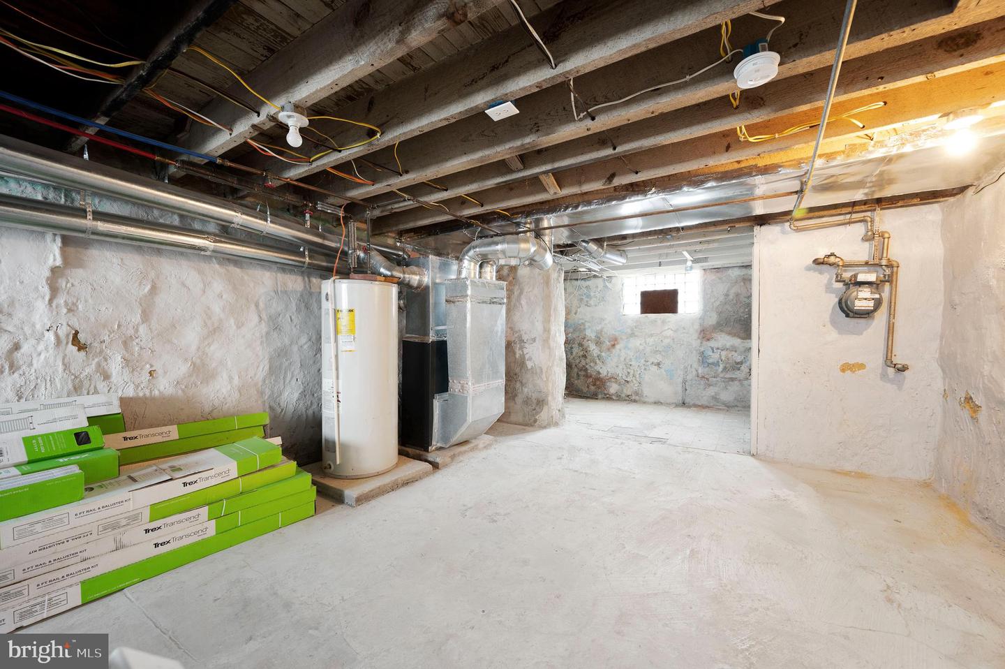 Unfinished basement with exposed joists, HVAC equipment, and stacked Trex decking boxes.