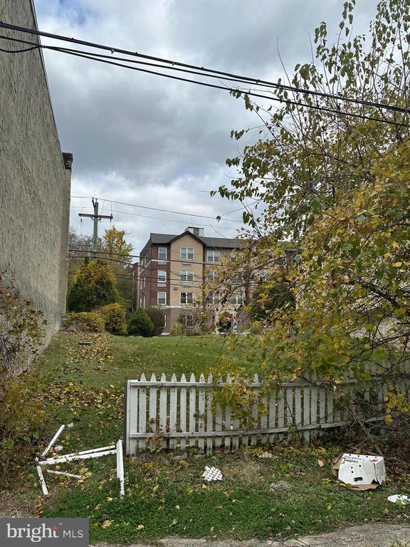 Grassy side yard with a white picket fence and autumn foliage.