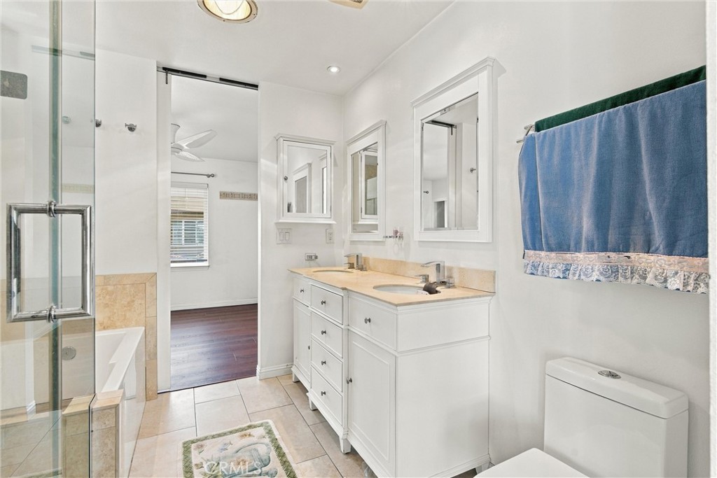 Bathroom with a double-sink vanity, large mirrors, and glass-enclosed shower.