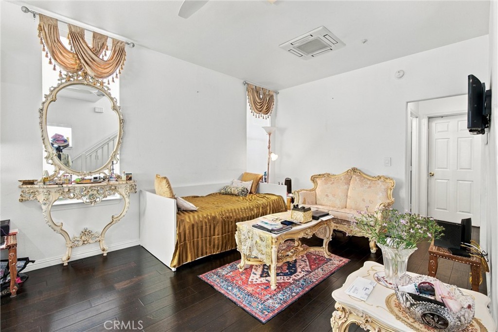 Bedroom with a gold-covered bed, ornate cream sofa, and decorative vanity.