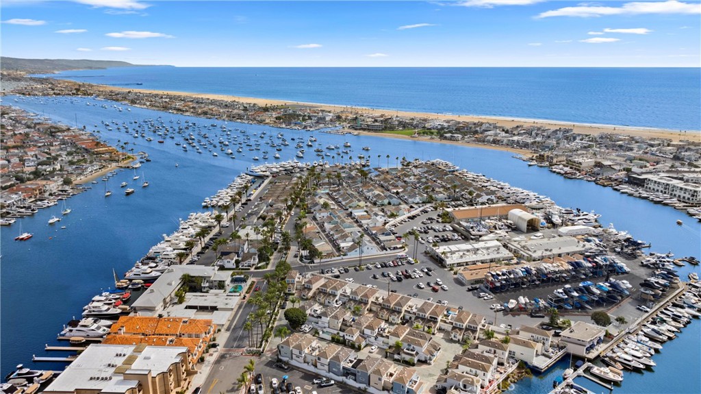 Aerial view of a boat-filled harbor, waterfront homes, and the Pacific shoreline.