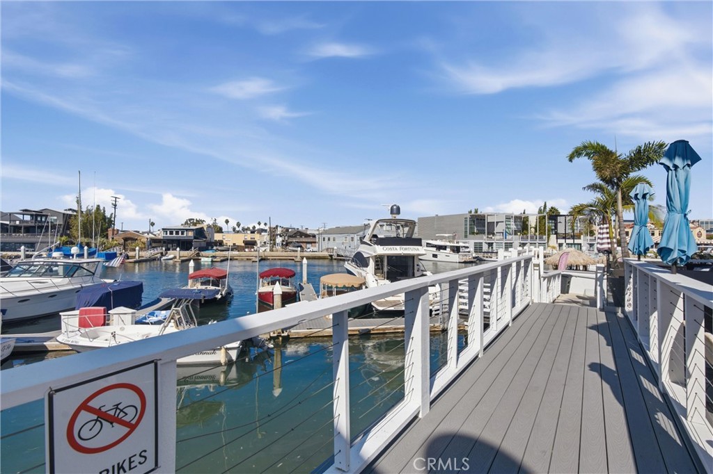 Marina boardwalk beside moored boats, with white railings and blue umbrellas.