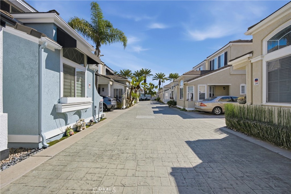 Attached coastal homes line a paved driveway beneath palm trees.