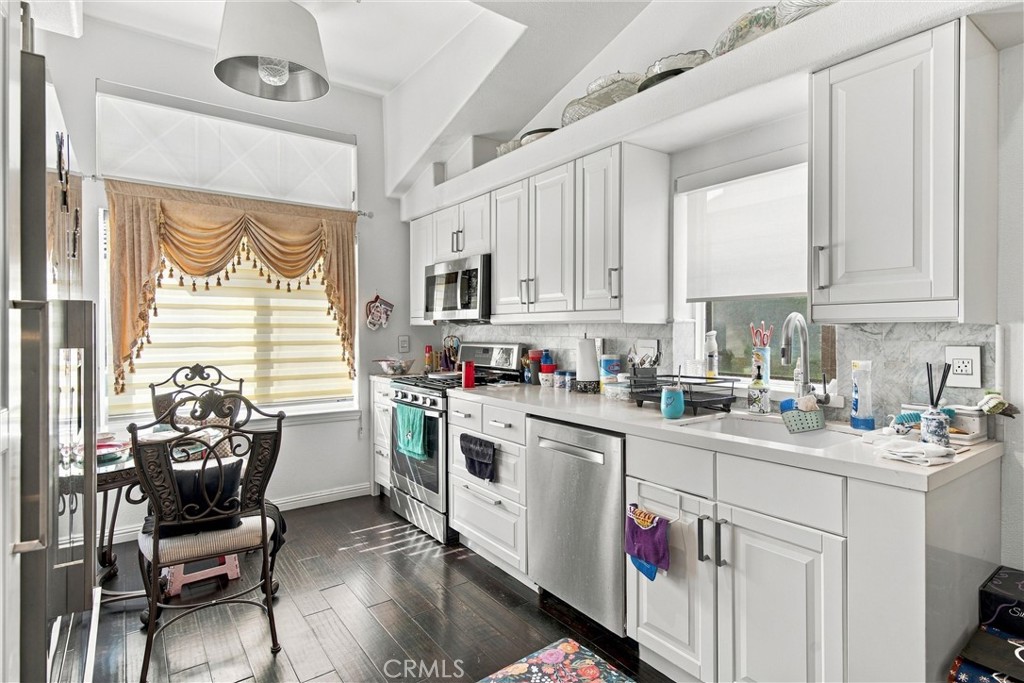 Kitchen with white cabinetry, stainless steel appliances, and a small dining table by the window.