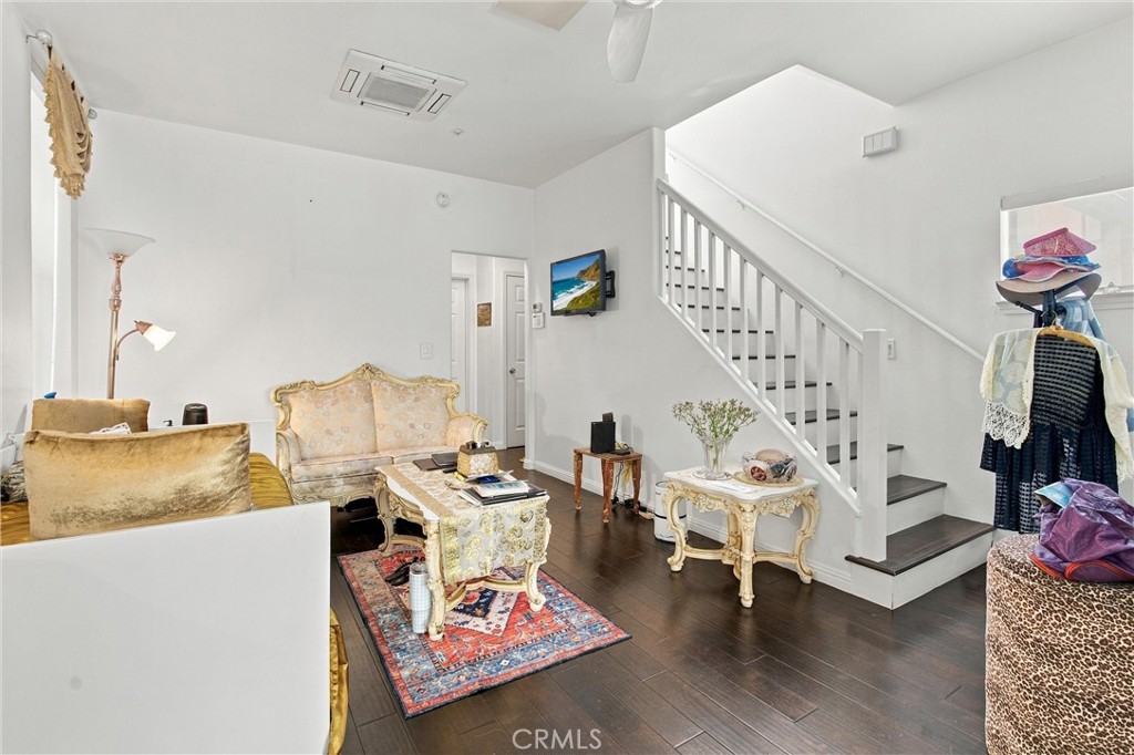 Furnished living room with ornate cream seating, a patterned rug, and a staircase with dark wood treads.