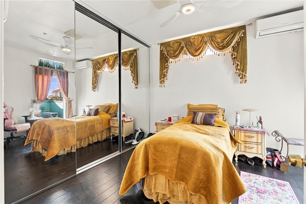 Bedroom with a mustard-yellow bedspread and mirrored sliding closet doors.