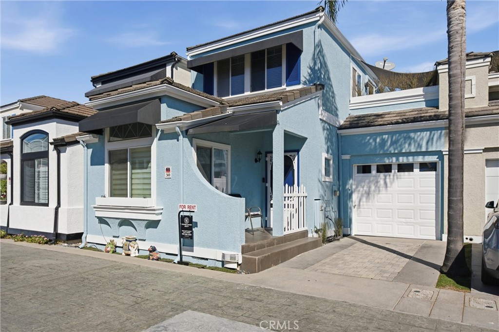 Blue two-story home with a covered entry, white picket gate, and attached garage.