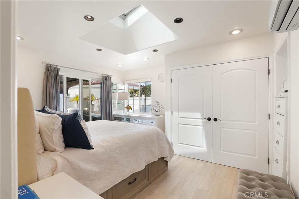 Bright bedroom with a large bed, skylight, and white double doors.