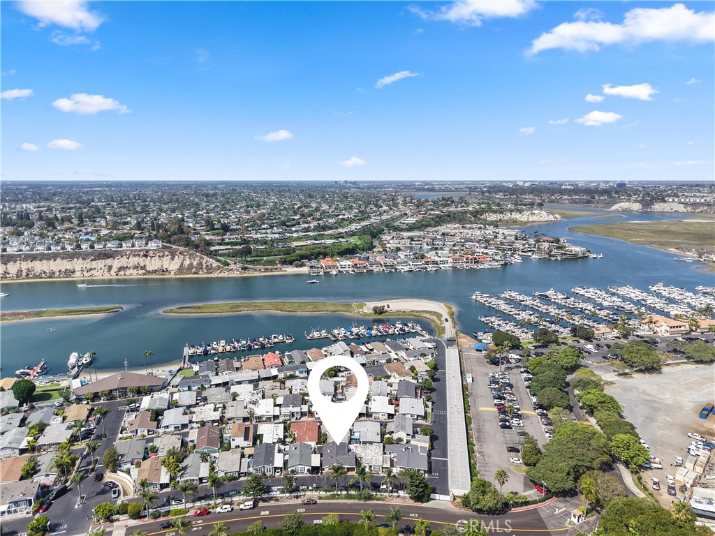Aerial view of a coastal neighborhood beside a marina, with the featured property marked by a white pin.