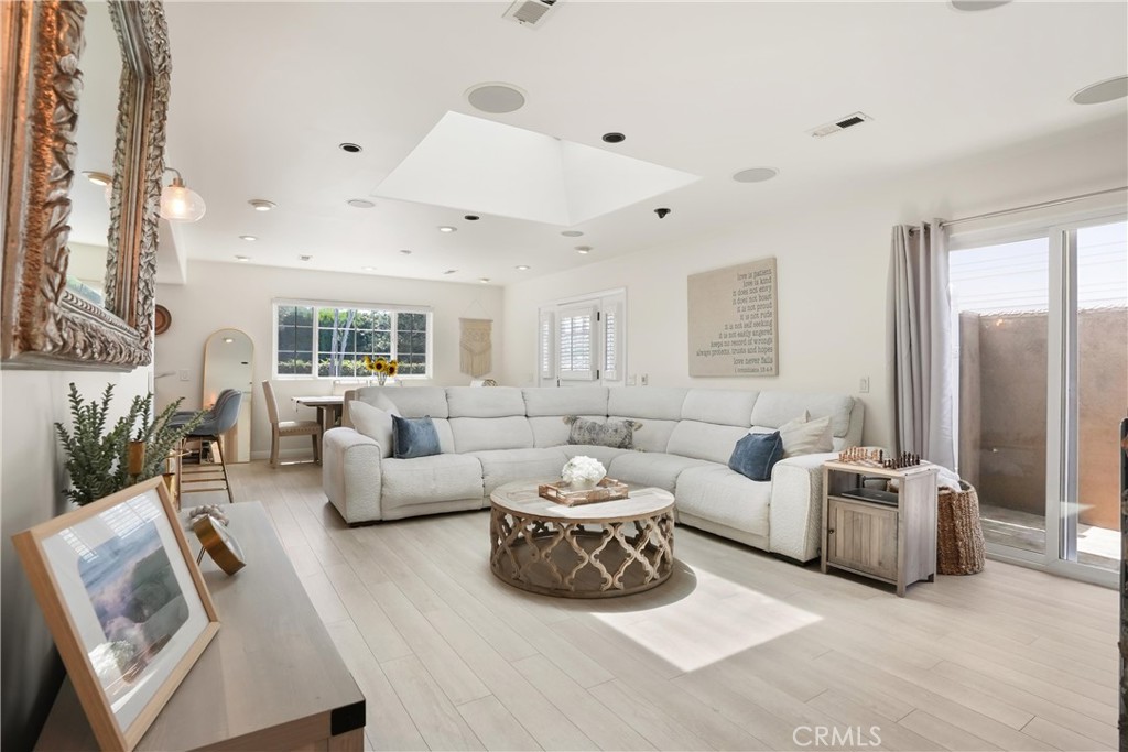 Bright living room with a white sectional, round coffee table, and sliding glass doors to a patio.