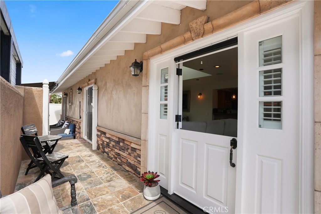 Tiled patio with black seating and open white French doors.