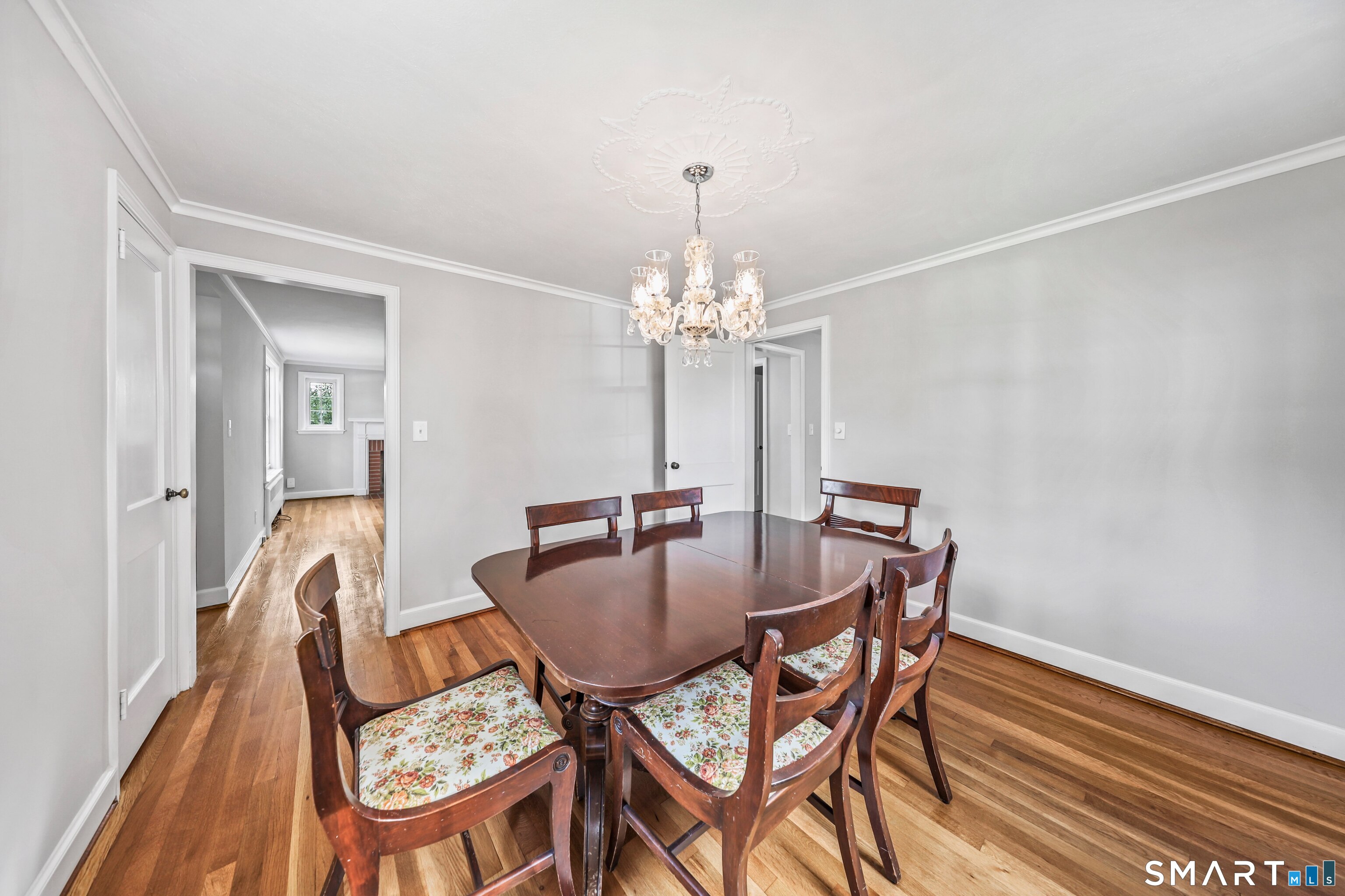Dining room with a dark wood table, floral-seat chairs, hardwood floors, and a chandelier.