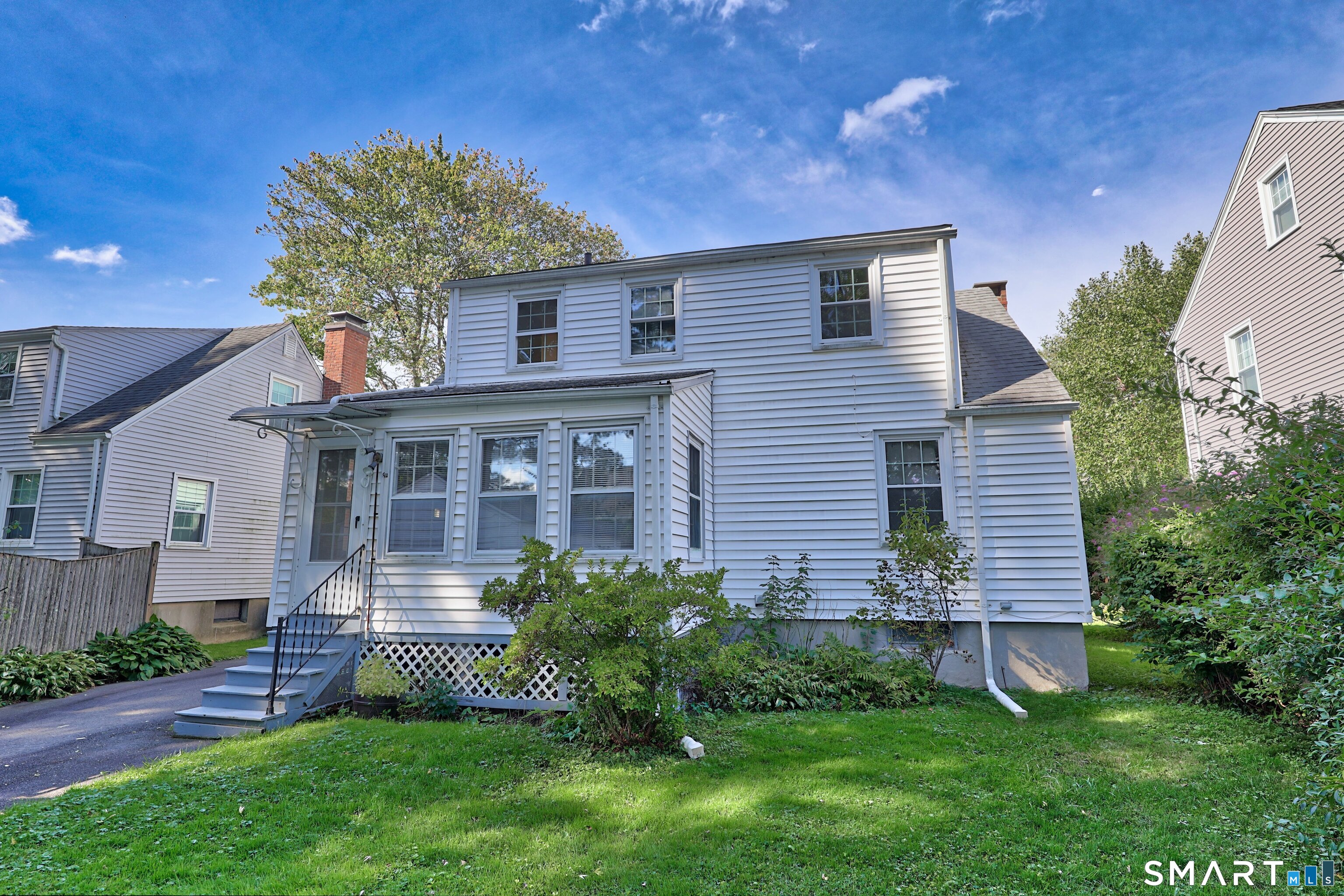 White two-story house with a covered entry, front steps, and a green lawn.