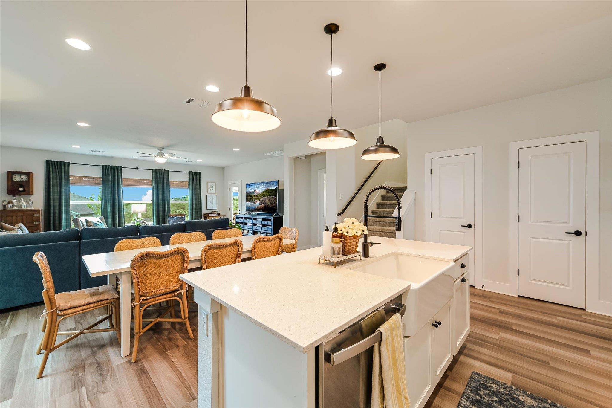 Open-plan kitchen with a large white island and sink beside a dining table and dark blue sectional.