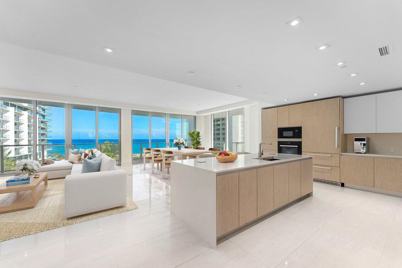 Open-plan condo kitchen with a large island and floor-to-ceiling windows overlooking the ocean.