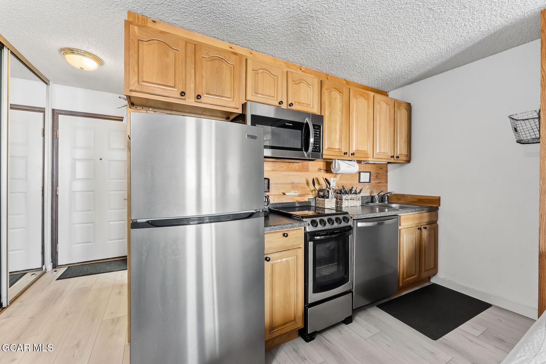 Kitchen with honey-colored cabinets, stainless steel appliances, and a wood backsplash.